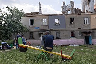 Menschen vor einem zerstörten Haus in Charkiw.