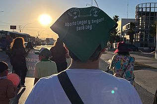 Eine Frau mit grünem Halstuch auf dem Kopf demonstriert in Ciudad Juárez für das Recht auf Selbstbestimmung.