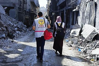 Gesundheitsarbeiter:innen von PMRS laufen durch Ruinen in Gaza