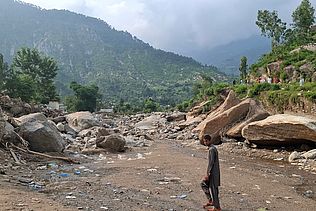 Ein Junge läuft durch das inzwischen trockene Bett einer Schlammlawine.